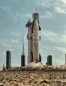 SpaceX Starship beside fully stacked ship on launch tower at Starbase